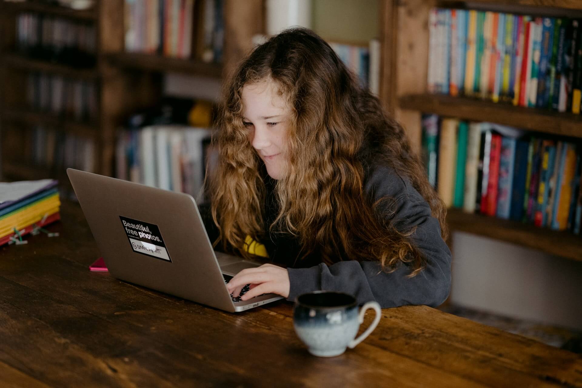 young girl in school library looking at laptop