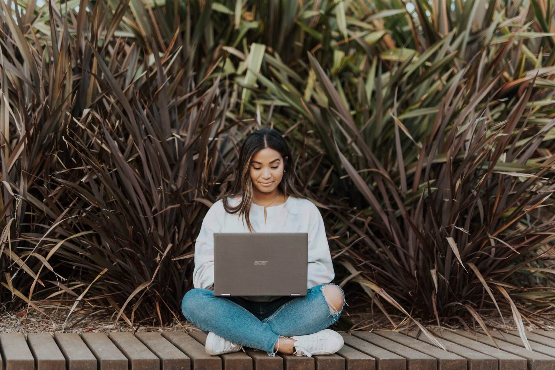 girl sitting on bench using laptop