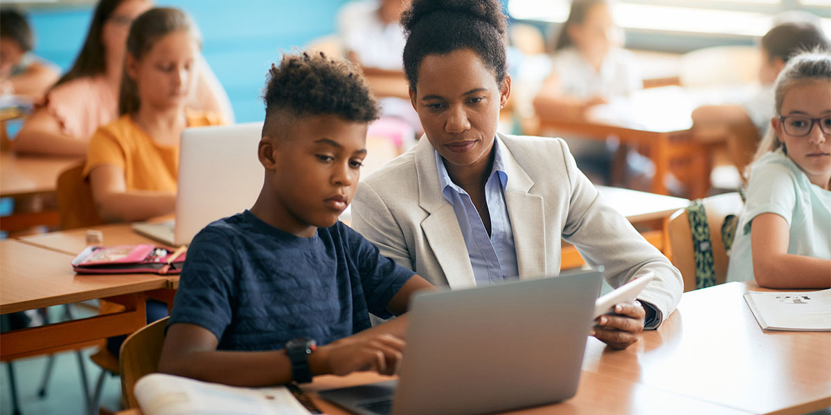 student and teacher looking at laptop