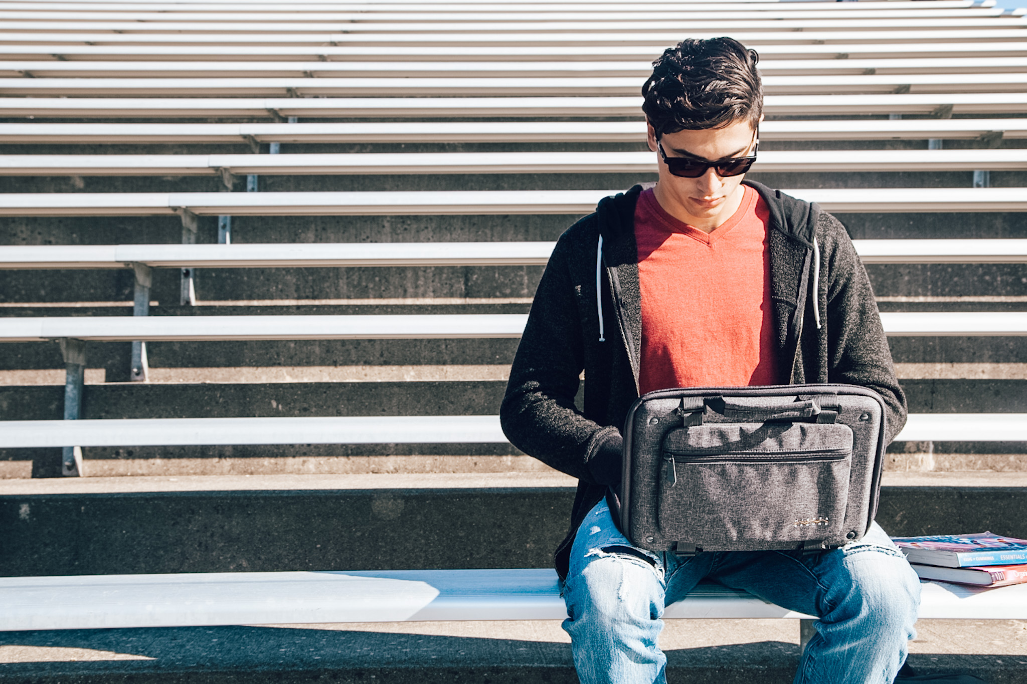 student sitting on bleechers using laptop in higher ground case