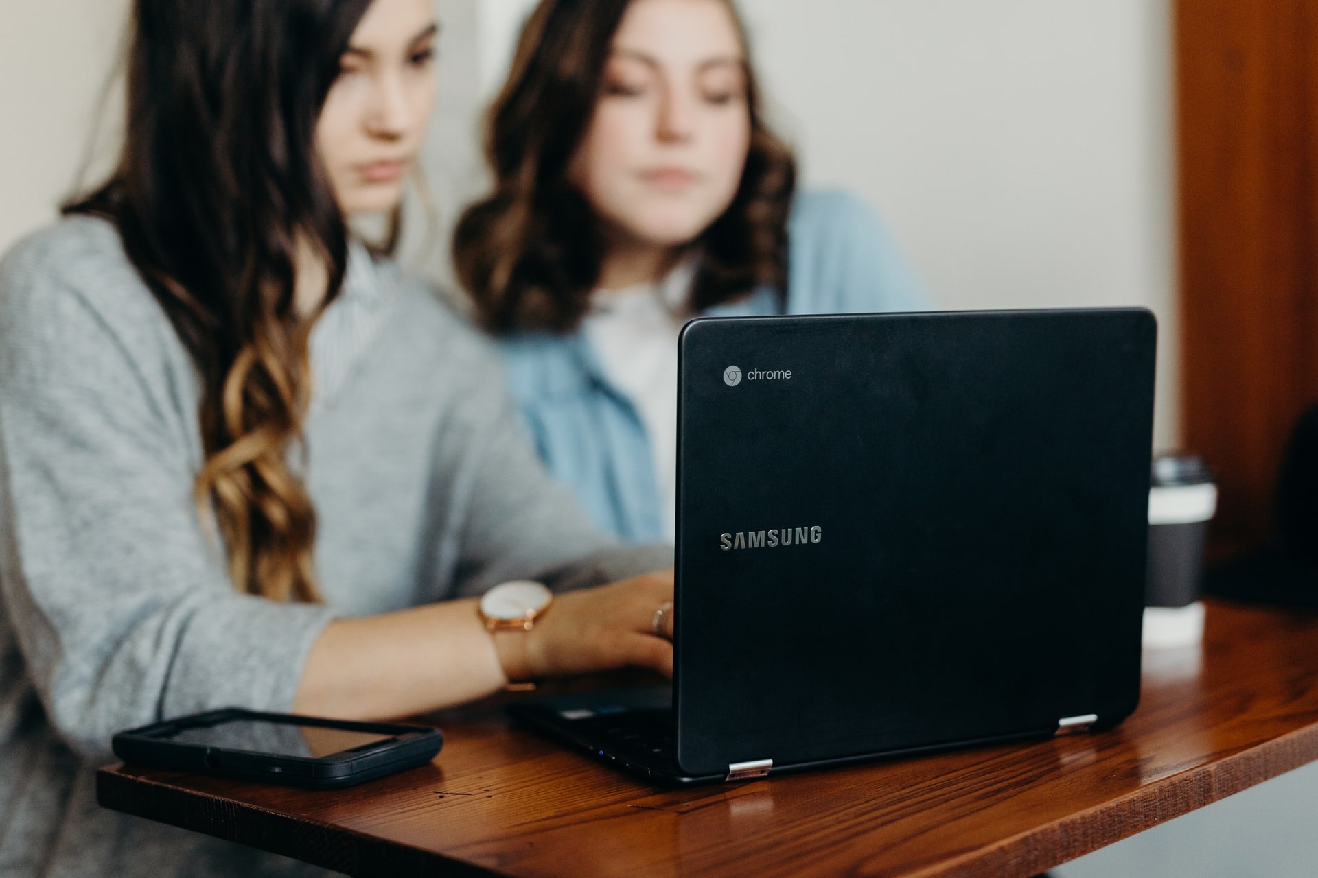 two girl students using chromebook laptop