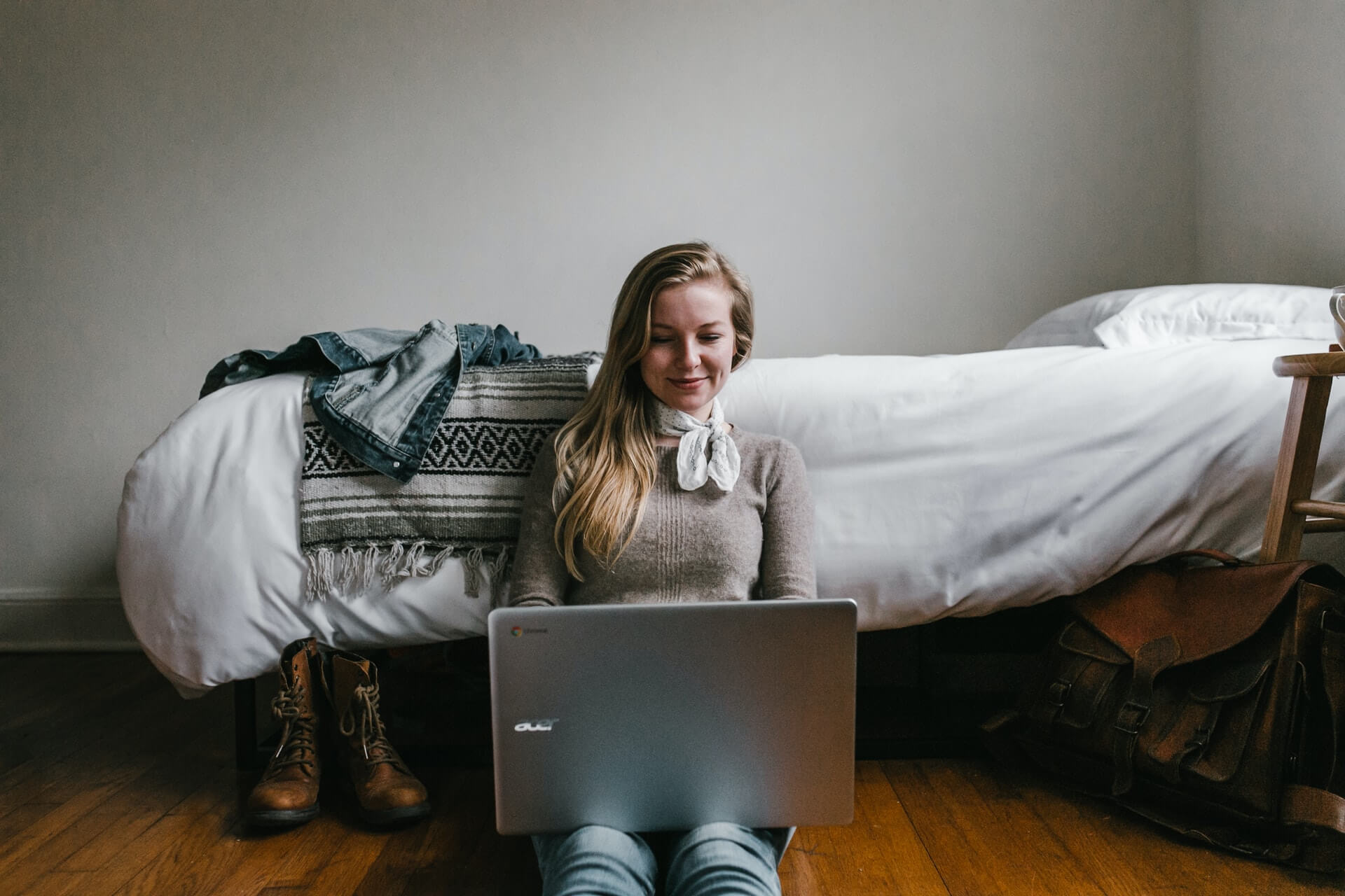 girl sitting on floor in dorm room and using laptop
