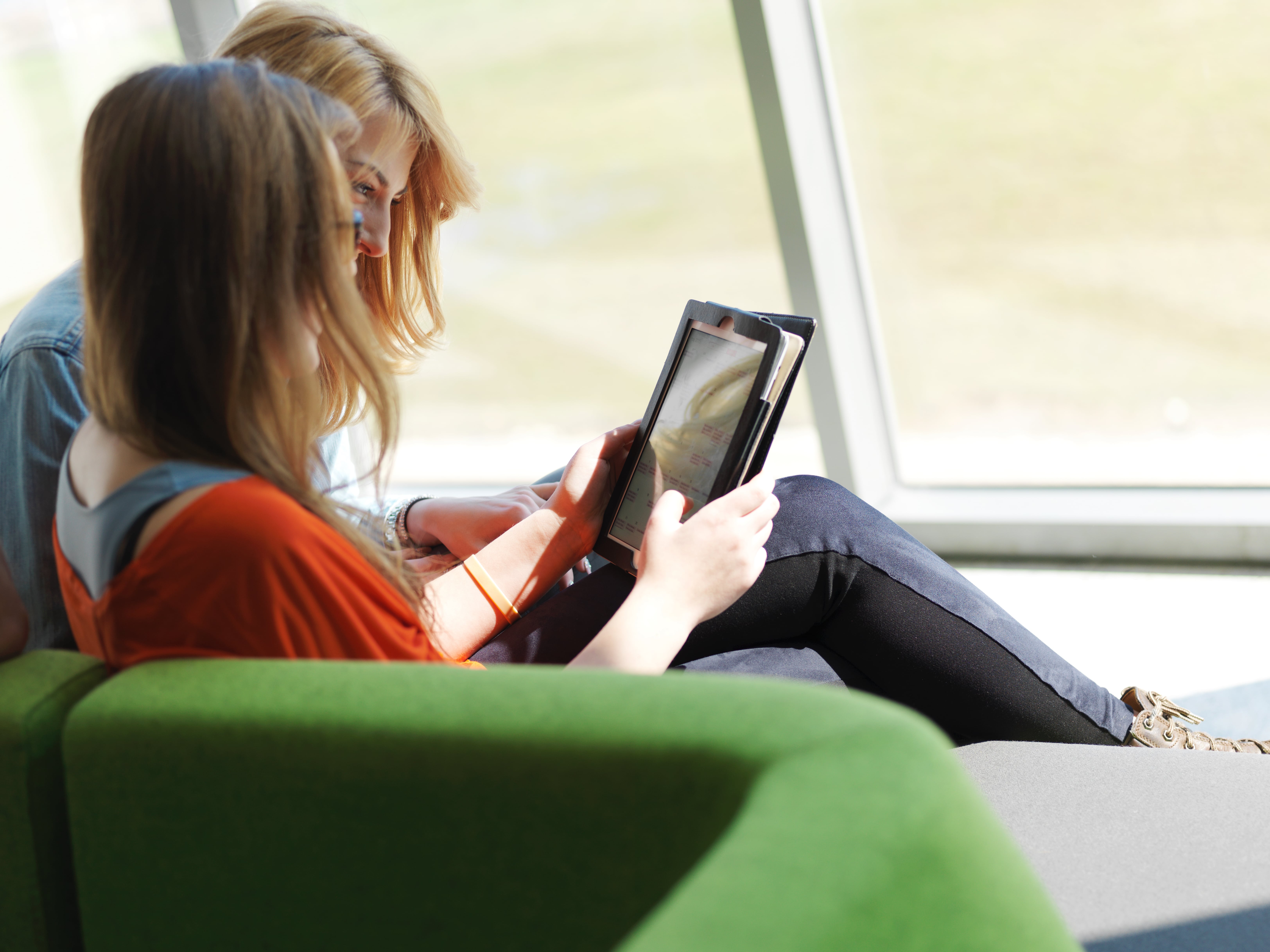 student sitting on hallway couch using tablet